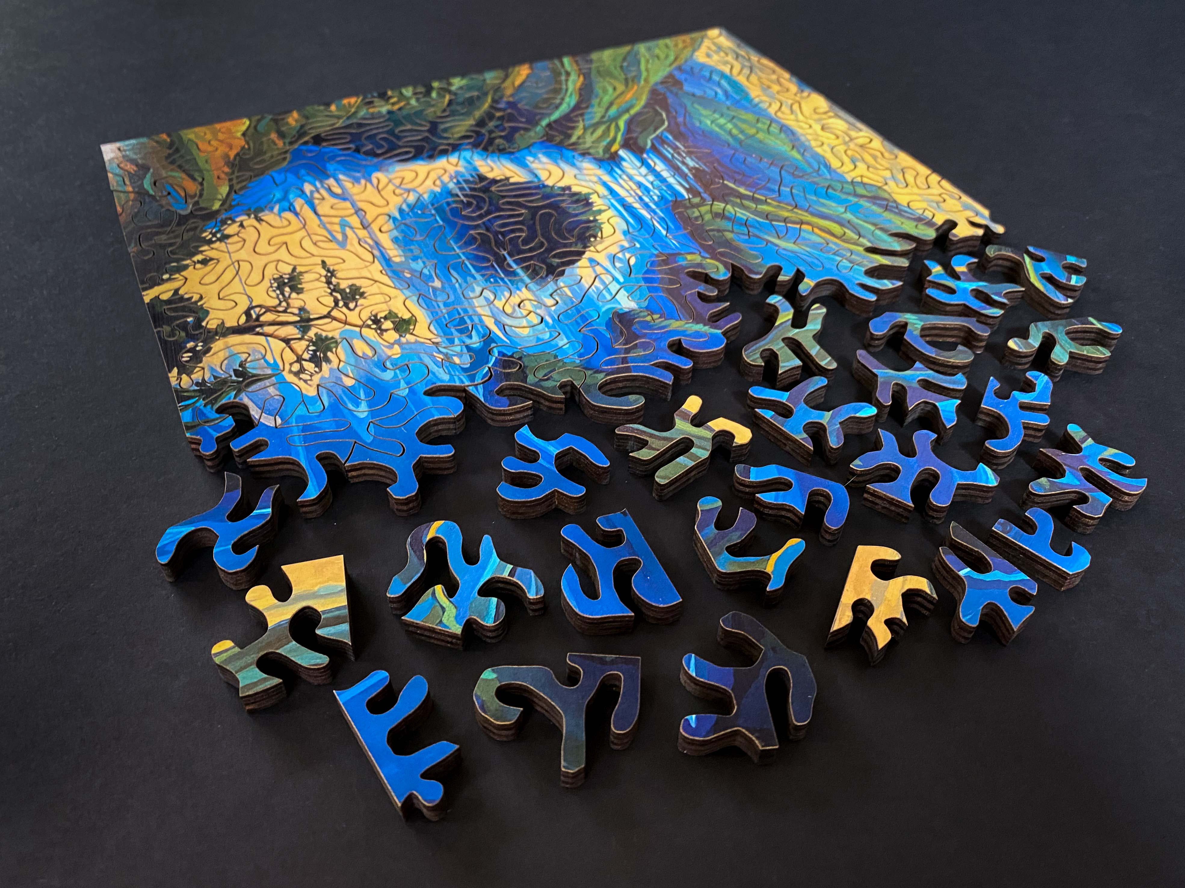 Shawn O'Keefe Jocelyn Hill wood jigsaw puzzle with colorful illustrated design and interlocking pieces on a flat surface.